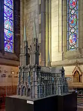 Photographie en couleurs de la maquette de la cathédrale vue de trois-quarts face présentant deux grandes tours pointues en façade. La maquette est à l'intérieur de la cathédrale.