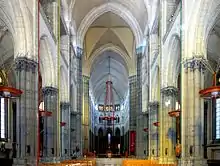 Photographie en couleurs de l'enfilade des quatre dernières travées de la nef avec au centre le chœur et au fond la Sainte Chapelle.