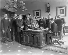 Le secrétaire d'État John Hay signe un traité de paix avec l'Espagne sur le Resolute desk dans le bureau du président McKinley, alors situé au 1er étage de la résidence exécutive de la Maison-Blanche (actuelle Lincoln Bedroom) c. 1899.