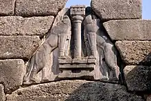 Détail du bas-relief de la porte des Lionnes : Deux lions rampants se faisant face de part et d'autre d'une colonne, les pattes avant posées sur deux autels biconcaves.