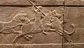 Le roi Assurbanipal, monté à cheval, plonge une lance dans un lion qui se jette sur lui. Bas-relief du palais nord de Ninive. British Museum.