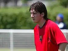Photographie couleur. Lionel Messi revêtant un t-shirt rouge aux couleurs du FC Barcelone.