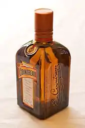 Photographie d'une bouteille de Cointreau, rectangulaire et de couleur orangée, vue de trois-quarts avant.