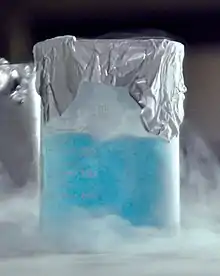 Un liquide bleu clair dans un récipient entouré de brumes.