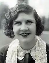 Photographie d'une jeune femme aux cheveux ondulés ramenés sur le côté et portant un foulard en dentelle