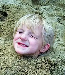 Tête d'un enfant sortant du sable