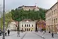 Côté sud de la place, vu vers l'est ; au fond, le bâtiment de la Philharmonie et, au-delà, le château de Ljubljana ; à gauche commence le square central.