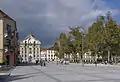 Côté sud de la place, vu vers l'ouest ; au fond, façade de l'église de la Trinité.