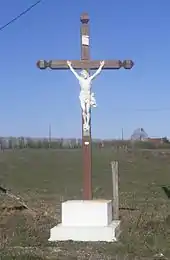 Photographie en couleurs d'un monument en bois et pierre représentant une Crucifixion.