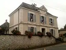 Cliché couleur d'un bâtiment. Porte « mairie » au fronton, drapeaux français et européen aux fenêtres, sirène au sommet.