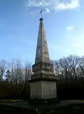 Photographie en couleurs d'un monument en pierre en forme de pyramide très élancée sur un socle cubique.