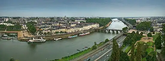 Photographie panoramique d'une rivière dans la ville, un port à gauche, une autoroute à droite, un pont.