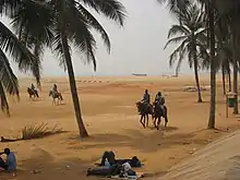 Deux cavaliers dans un paysage de désert avec des palmiers