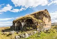 Un bâtiment en décomposition, coiffé d'herbes abondantes, dont on devine encore l'emplacement du toit. Des restes de voutes sur le côté donnent une impression religieuse.