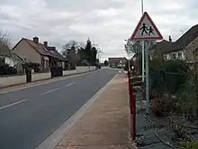 Traversée de la route départementale dans le village. Un panneau indique un endroit fréquenté par les enfants.