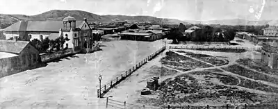 L'église "Old Plaza" (vieille place) qui fait face au Plaza, 1869. Le réservoir en briques au milieu de la place est le terminus original du Zanja Madre.