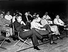 Un groupe d'hommes assis dans des chaises pliantes.