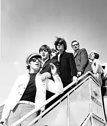 photographie en noir et blanc de six personnes en haut d’une passerelle à la sortie d’un avion de la compagnie Iberia.