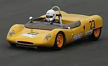 Voiture jaune avec un pilote en casque blanc.