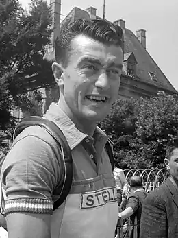 Photographie en noir et blanc d'un cycliste portant un maillot bicolore marqué Stella.