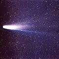 Gros plan sur une comète, sa queue et sa chevelure, sur un fond constellé.