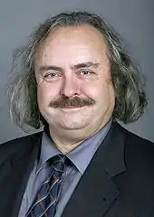 Portrait d'un homme aux cheveux gris et portant une moustache.
