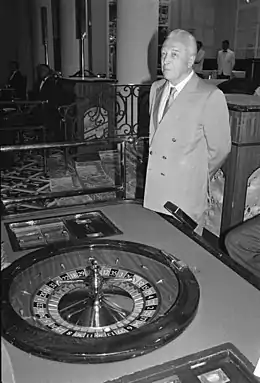 Vue noir et blanc d'un homme en costume gris derrière une table de roulette.