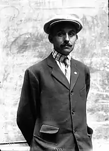 Portrait en noir et blanc d'un homme vêtu d'un costume et portant une casquette.