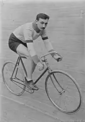 Photographie en noir et blanc d'un coureur cycliste sur un vélodrome en bois.