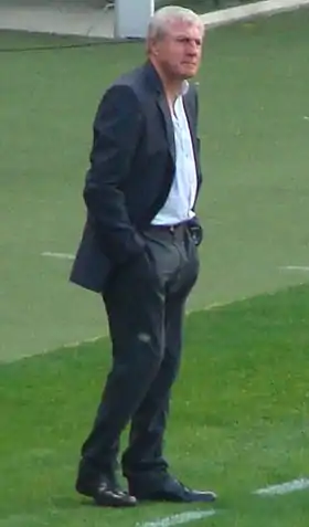 Homme en costume debout au bord d'un terrain de football