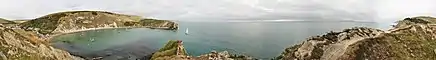 Photographie panoramique d'une crique bien abritée en bord de mer.