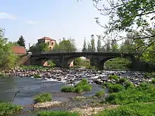 Un pont à trois arches sous laquelle s’écoule une rivière entre de grands galets.