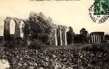 carte postale en noir et blanc représentant les arches ruinées d'un aqueduc.