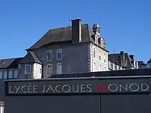 Photographie en couleurs d'un lycée, avec l'inscription : "LYCEE JACQUES MONOD.