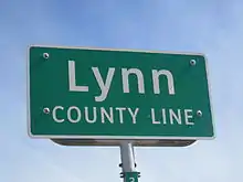 Panneau de signalisation vert sur fond blanc avec inscription Lee County Line