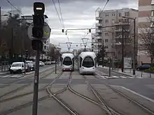 Photographie couleur montrant deux voies de tramway situées sur la partie centrale d'une avenue ; deux tramways s'y croisent.