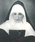 Photo noir et blanc d'une religieuse âgée, portant un crucifix en travers sur la poitrine
