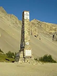 Photographie d'un monument en forme de colonne rendant hommage à plusieurs coureurs cyclistes au col d'Izoard.