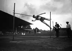 Photographie en noir er blanc d'un athlète effectuant un saut en hauteur.