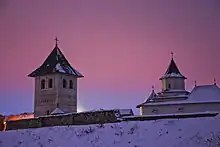 Vue de la chapelle Saint-Grégoire. Elle se présente sous la forme d'une tour à deux niveaux et au toit pointue. En arrière-plan se situe l'abbatiale Saint-Auxence.