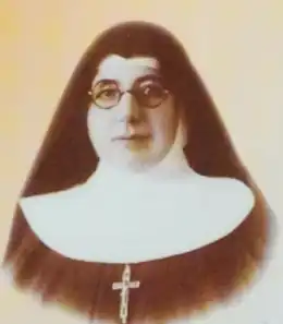 Photo monochrome d'une religieuse avec lunettes, portant une croix pectorale