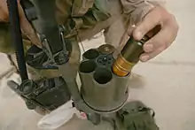 Photographie d'un soldat en train d'insérer des grenades de 40 mm dans le barillet d'un lance-grenades multiple.