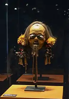 Tête trophée, Mundurucú. Os, cheveux, dents, cire, plumes, fibres. H. 43 cm. v. 1880. Brésil.