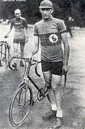 Photographie en noir et blanc d'un coureur cycliste se tenant debout à côté de son vélo.