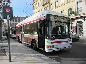 Photographie d'un mât-totem plus sobre devant lequel est stationné un trolleybus numéroté S6 à destination de l'Hôtel de Ville.