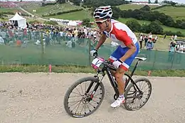  Homme debout sur les pédales d'un VTT, portant une tenue bleu-blanc-rouge.