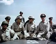 Huit hommes assis en uniformes kakis