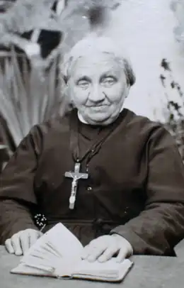 photo en noir et blanc d'une religieuse âgée, un crucifix sur la poitrine, la main sur un livre.