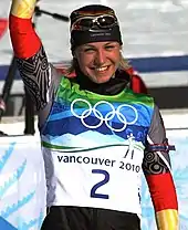 Magdalena Neuner, sur le podium du départ en ligne, saluant de la main droite