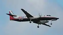 Photo couleur de l'extérieur d'un avion de ligne bimoteur à hélices en vol, prise par le dessous de l'appareil, depuis le sol.